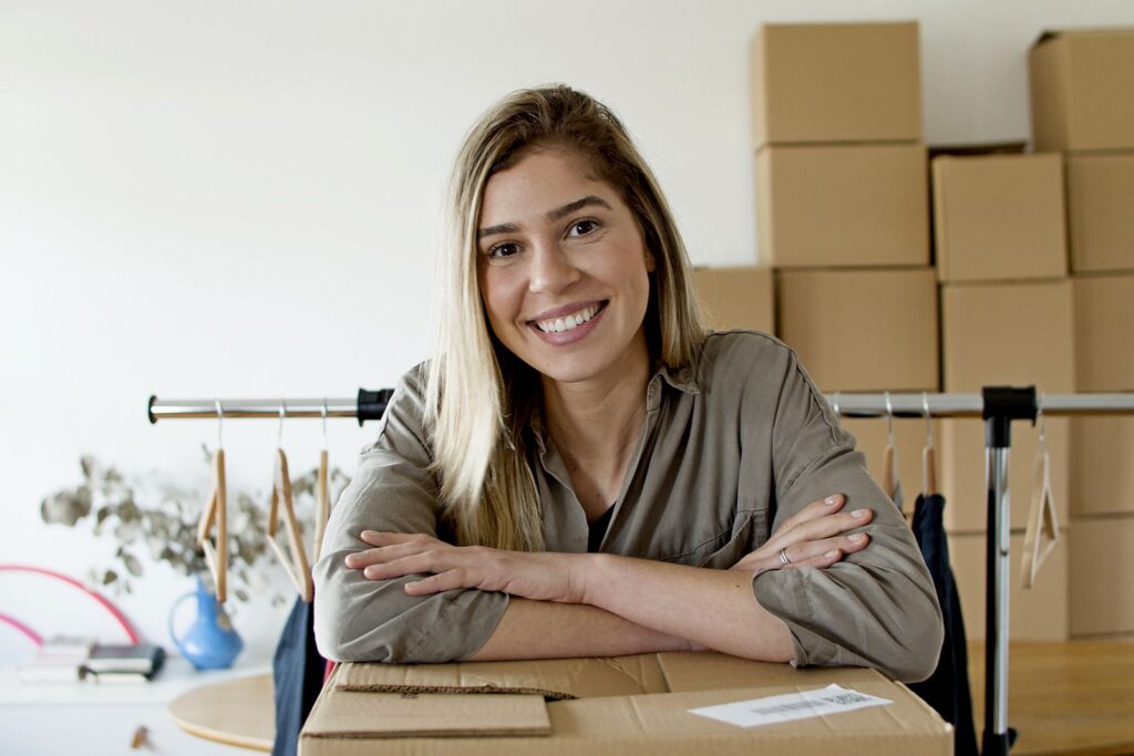 Microempreendedora sorrindo enquanto organiza pacotes de vendas do seu pequeno negócio